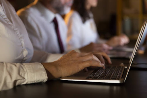 Professionals working on laptops in a row at an event.